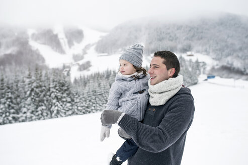 Vater hält Tochter in Winterlandschaft - HAPF00961