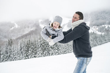 Father playing with daughter in winter landscape - HAPF00962