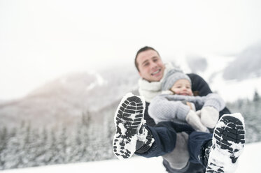 Father holding daughter in winter landscape - HAPF00963