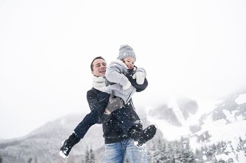 Vater spielt mit Tochter in Winterlandschaft, lizenzfreies Stockfoto
