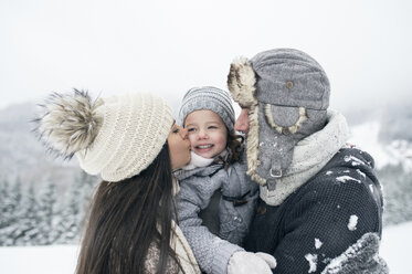 Familie in Winterlandschaft mit Mutter küsst Tochter - HAPF00966