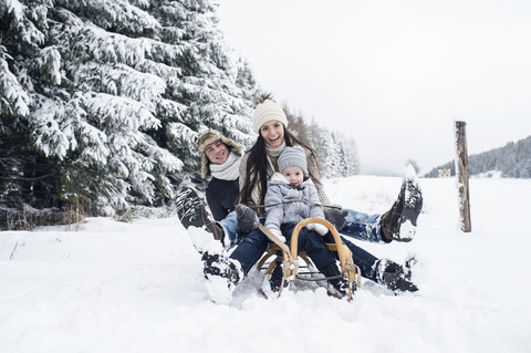 Glückliche Familie auf Schlitten in Winterlandschaft, lizenzfreies Stockfoto