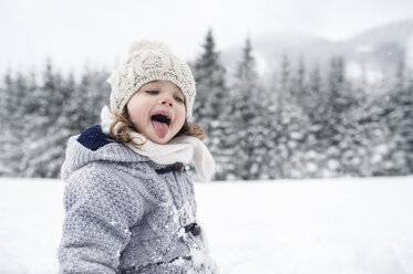 Mädchen in Winterlandschaft fängt Schneeflocken mit ihrer Zunge - HAPF00971