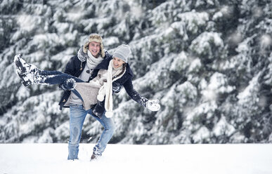 Mann trägt Freundin in Winterlandschaft - HAPF00984