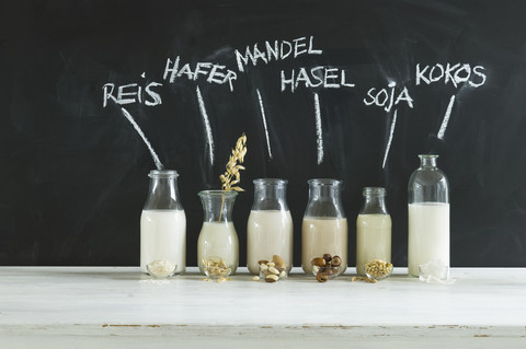 Glasflaschen mit verschiedenen veganen Milchsorten, lizenzfreies Stockfoto
