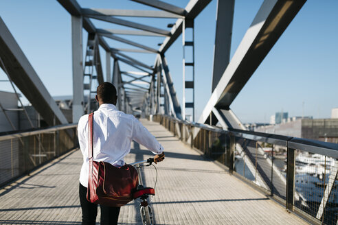 Mann schiebt Fahrrad auf einer Brücke - JRFF00918