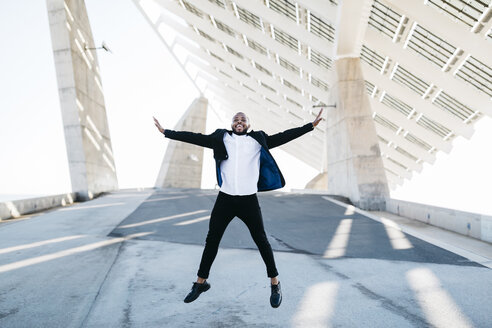 Vital businessman jumping under solar panels - JRFF00946