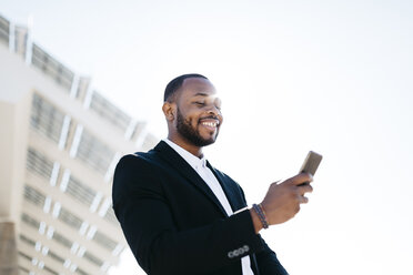 Smiling businessman looking at cell phone - JRFF00953