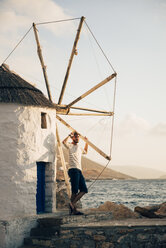 Griechenland, Amorgos, Aegialis, Mann posiert neben Windmühle - GEMF01142