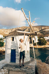 Griechenland, Amorgos, Aegialis, Mann hält die Flügel einer Windmühle - GEMF01144