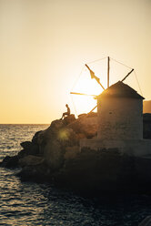 Griechenland, Amorgos, Aegialis, Silhouette eines Mannes, der in der Nähe einer Windmühle bei Sonnenuntergang sitzt - GEMF01148