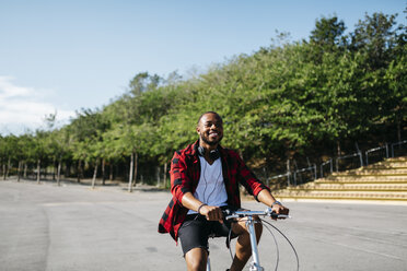 Lächelnder Mann fährt mit dem Fahrrad durch einen Park - JRFF00962