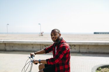 Mann auf Fahrrad in Strandnähe - JRFF00975