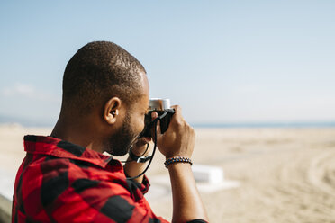 Mann fotografiert mit einer altmodischen Kamera in Strandnähe - JRFF00977