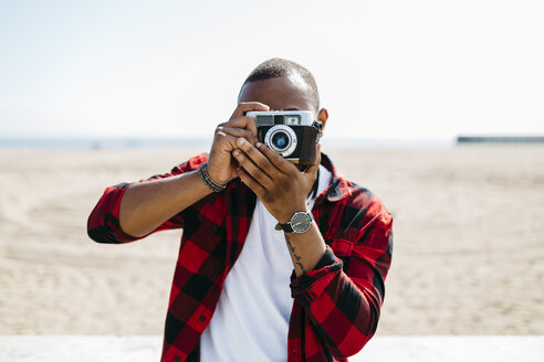 Mann fotografiert mit einer altmodischen Kamera in Strandnähe - JRFF00980