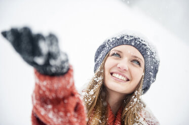 Smiling young woman in heavy snowfall - HHF05414