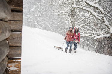 Two young women with sledges in heavy snowfall - HHF05416