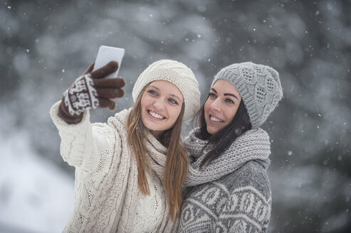 Zwei junge Frauen machen ein Selfie im Schneefall - HHF05417