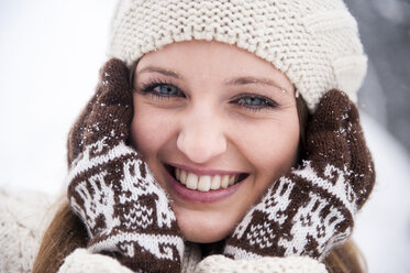 Portrait of smiling young woman in snowfall - HHF05420