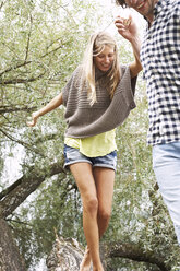 Young couple balancing on a tree trunk - FSF00567