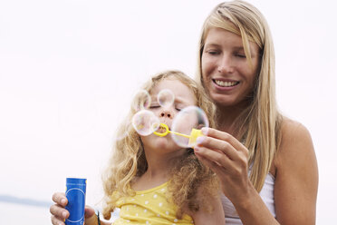 Mother and daughter blowing soap bubbles - FSF00578