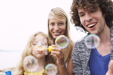 Parents with daughter blowing soap bubbles - FSF00581