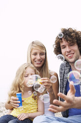 Parents with daughter blowing soap bubbles - FSF00582