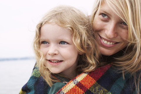 Mutter mit Tochter in einer Decke eingewickelt, lizenzfreies Stockfoto