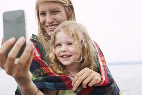 Mutter mit Tochter in einer Decke eingewickelt ein Selfie machen - FSF00585