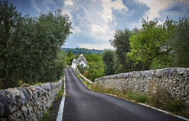 Italien, Apulien, Landstraße und Trullo hinter Steinmauer und Olivenbäumen - DIKF00215