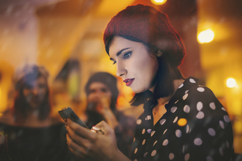 Young woman wearing red hat behind windowpane of a pub in the evening stock photo