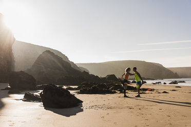 France, Crozon peninsula, sportive young couple stetching on the beach - UUF08616