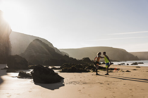 Frankreich, Halbinsel Crozon, sportliches junges Paar beim Stetching am Strand - UUF08616