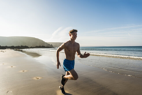 Frankreich, Halbinsel Crozon, junger Mann läuft am Strand - UUF08626