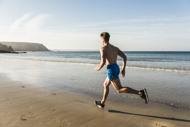 Frankreich, Halbinsel Crozon, junger Mann läuft am Strand - UUF08627