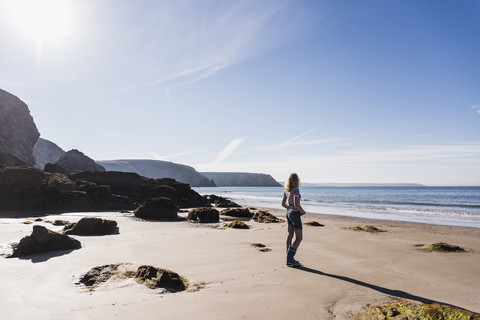 Frankreich, Halbinsel Crozon, junges Mädchen am Strand stehend, lizenzfreies Stockfoto