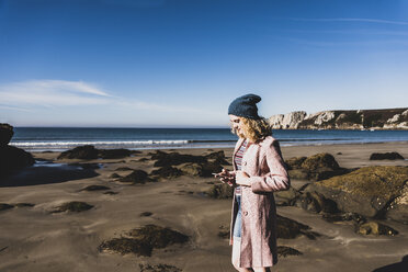 Frankreich, Halbinsel Crozon, junges Mädchen mit Handy am Strand - UUF08645