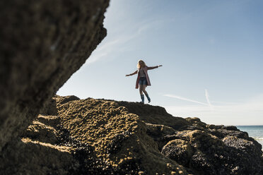 Frankreich, Halbinsel Crozon, junges Mädchen, das auf einem Felsen an der Küste spazieren geht - UUF08649