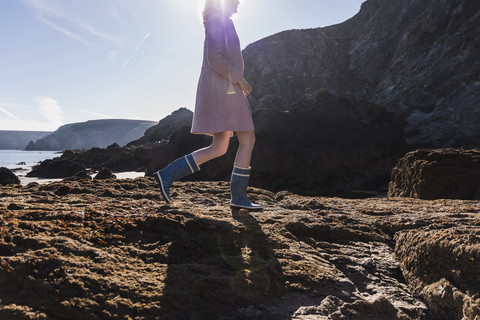 Frankreich, Halbinsel Crozon, junges Mädchen, das auf einem Felsen am Strand spazieren geht, lizenzfreies Stockfoto