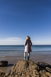 Frankreich, Halbinsel Crozon, junges Mädchen steht auf einem Felsen am Strand - UUF08654