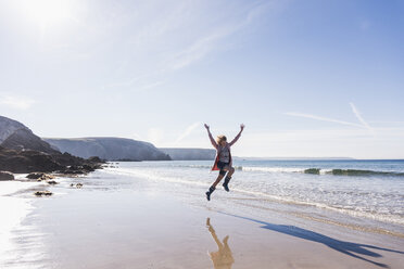 Frankreich, Halbinsel Crozon, jugendliches Mädchen, das am Strand vor Freude springt - UUF08655