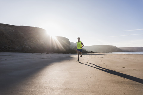 Frankreich, Halbinsel Crozon, junger Mann läuft am Strand, lizenzfreies Stockfoto