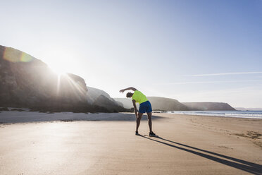Frankreich, Halbinsel Crozon, sportlicher junger Mann beim Stretching am Strand - UUF08680