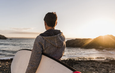 Frankreich, Bretagne, Halbinsel Crozon, Frau am Strand bei Sonnenuntergang mit Surfbrett - UUF08685