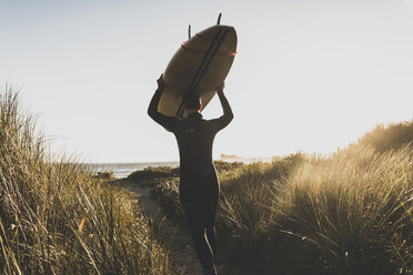 Frankreich, Bretagne, Halbinsel Crozon, Frau geht mit Surfbrett durch die Dünen - UUF08699