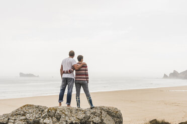 France, Bretagne, Crozon peninsula, couple standing on rock at the beach - UUF08728