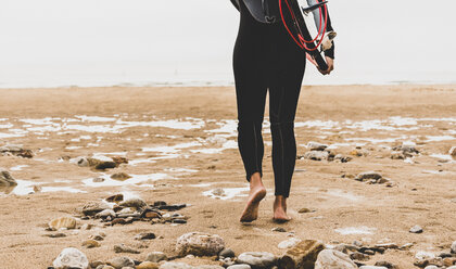 Frankreich, Bretagne, Halbinsel Crozon, Frau geht am Strand mit Surfbrett - UUF08729