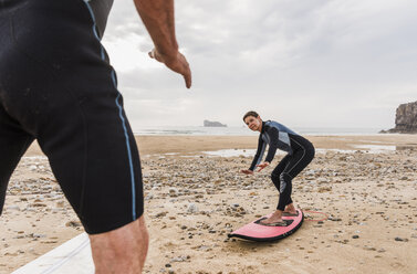 Frankreich, Bretagne, Halbinsel Crozon, Mann bringt Frau am Strand das Surfen bei - UUF08735