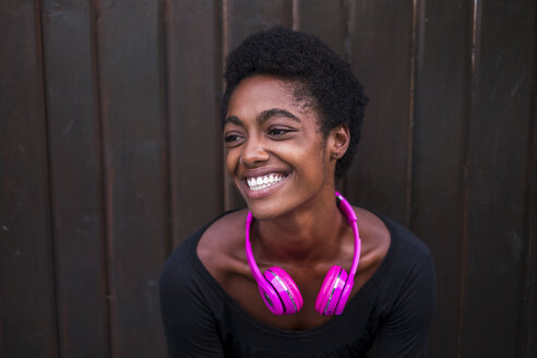 Porträt einer lachenden Frau mit rosa Kopfhörern - SIPF00934