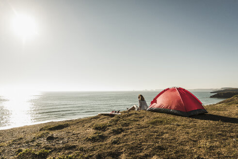 Jugendliches Mädchen mit Surfbrett beim Camping am Meer - UUF08746